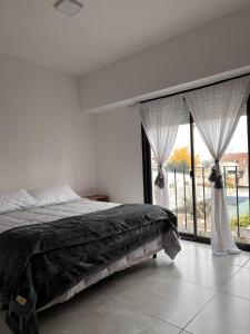 a bedroom with a bed and a large window at Olivos Lujan in Luján