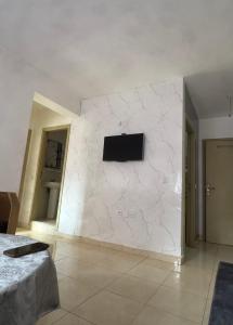 a room with a white wall with a tv on it at Perfect Stay Apartment 10 min to airport ibn battouta and beach in Tangier
