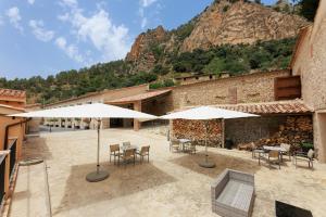 a patio with tables and umbrellas in front of a building at Hotel de La Trucha in Villarluengo