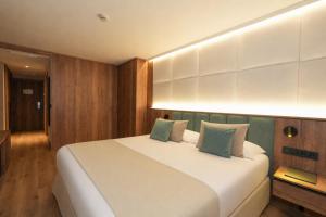 a bedroom with a large white bed with green pillows at Hotel Princesa Parc Excellence in Arinsal +56 photos
