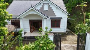 a white house with red windows and a gate at Tay Na Bon Homestay in Ha Giang