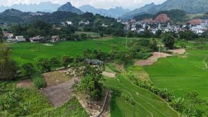 an aerial view of a green field with mountains in the background at Tay Na Bon Homestay in Ha Giang