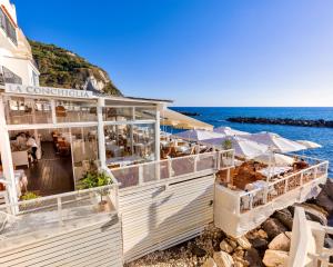 a restaurant on the beach with the ocean in the background at Roccobarocco Boutique Hotel in Sant'Angelo D'Ischia