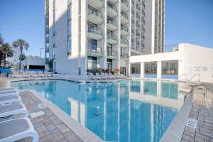 a swimming pool with white chairs and a building at Ocean Park Resort in Myrtle Beach