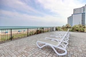 a row of white chairs on a balcony with the beach at Ocean Park Resort in Myrtle Beach