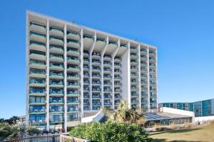 a large white building with palm trees in front of it at Ocean Park Resort in Myrtle Beach