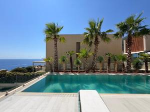 a swimming pool with palm trees in front of a building at Villa Azul in Palasë