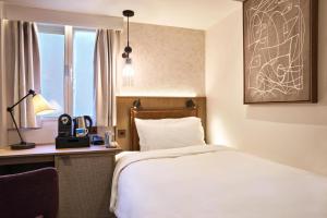 a hotel room with a bed and a desk and a window at Radisson Blu Hotel, London Euston Square in London