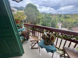 a balcony with a green door and a table and chairs at Blomst Casa Hostal in Jericó
