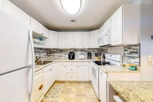 a white kitchen with white cabinets and a refrigerator at Whispering Woods #26 in Ocean City
