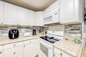 a kitchen with white cabinets and a stove top oven at Whispering Woods #26 in Ocean City +16 photos