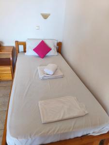 a bed with two towels and a pink pillow on it at studios Katerina A Lentas in Lentas