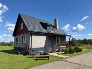 a black and white house with a table and a bench at Brīvdienu māja 1 in Kurmēni
