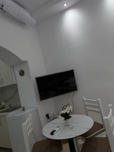 a living room with a table and a tv on a wall at Casa de Flori in Përmet