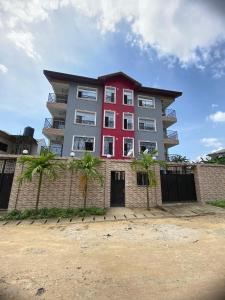 a red and gray building with palm trees in front of it at Résidence les Palaja in Douala
