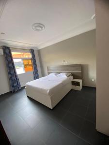 a bedroom with a white bed and a window at Résidence les Palaja in Douala