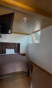 a bedroom with a bed with a television on the wall at La Casita de Merme in Oxapampa
