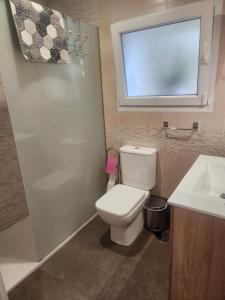 a bathroom with a toilet and a sink and a window at Apartamento Riberuca Playa in Suances