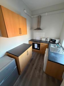 a kitchen with black counter tops and wooden cabinets at Stylish Bolton Stay Parking Walk to Town Centre in Farnworth +7 photos