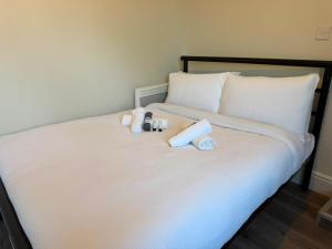 a white bed with two stuffed animals on it at Stylish Bolton Stay Parking Walk to Town Centre in Farnworth