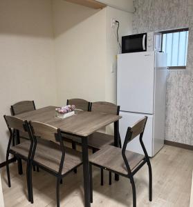 a dining room table with chairs and a white refrigerator at Lee house 佳 別荘 一戸建て貸切の宿 in Osaka