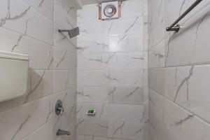 a bathroom with a shower with white marble tiles at Hotel Sky in Dwarka +35 photos