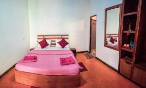 ein Schlafzimmer mit einem Bett mit rosa Laken und einem Spiegel in der Unterkunft Trailside Ella-Your Gateway to Ella Rock in Ella + 53 Fotos