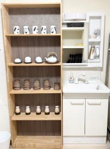 a kitchen with a sink and shelves with dishes at Lee house 佳 別荘 一戸建て貸切の宿 in Osaka
