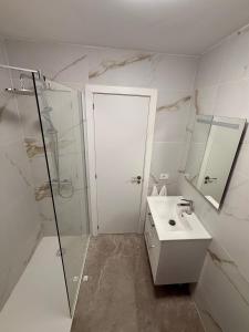 a white bathroom with a shower and a sink at Pool View Apartment Garden City in Costa de Adeje +5 photos