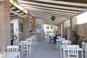 a restaurant with white tables and white chairs at Masseria SoleMare Gallipoli in Pizzo