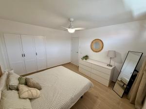 a white bedroom with a bed and a mirror at Pool View Apartment Garden City in Costa de Adeje