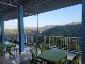 a balcony with tables and chairs and a view of the mountains at Vatiguesthouse in Shillong