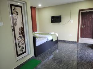 a room with two beds and a door with a television at Vatiguesthouse in Shillong