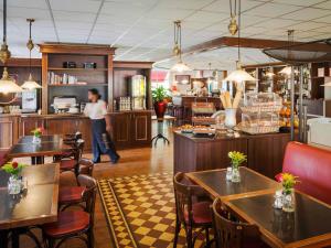 a man standing in a restaurant with tables and chairs at ibis Tilburg in Tilburg