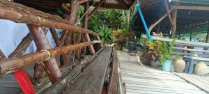 a wooden bench sitting on a porch with plants at Phaluay seefood Motel in Koh Phaluai