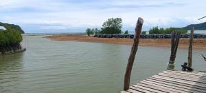 a wooden boat in the water next to a river at Phaluay seefood Motel in Koh Phaluai