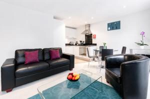 a living room with a couch and a table with a bowl of fruit at Roomspace Serviced Apartments - Capitol Square in Epsom