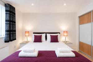 a bedroom with a large white bed with two lamps at Roomspace Serviced Apartments - Capitol Square in Epsom