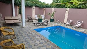 a swimming pool with chairs and a table and a patio at Green Land in Tbilisi City