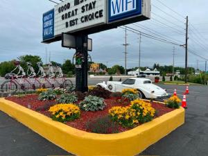 a sign for a car dealership with a flower bed at Wolf Inn Hotel in Sandusky