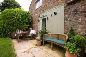 a patio with a bench and a table and a building at The Byre in Penrith