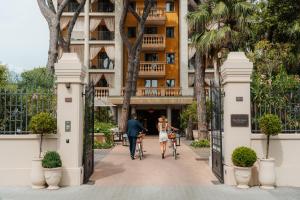 a man and a woman walking their bikes through the gates of a hotel at Grand Hotel Imperiale in Forte dei Marmi