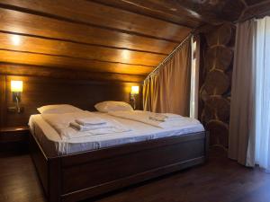 a bed in a room with a wooden wall at Villa ZRUB in Palyanytsya