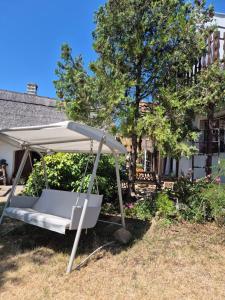 a white bed under an umbrella in a yard at Naplopó-lak in Ábrahámhegy