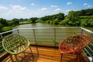 two chairs on a deck with a view of a river at Krishibid Resort 