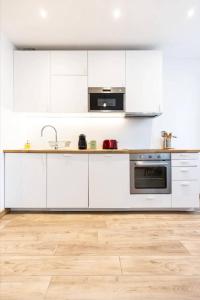 a kitchen with white cabinets and a wooden floor at Le Vivaldi - Studio Hypercentre Saint-Étienne in Saint-Étienne