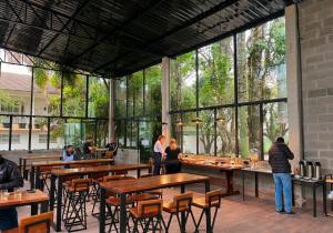 people standing in a restaurant with tables and windows at Ipê Hotel Jardins in Ponta Grossa