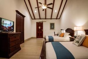 a bedroom with two beds and a flat screen tv at Hotel Plaza Colon - Granada Nicaragua in Granada