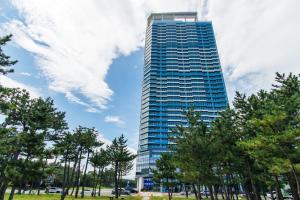 a tall blue building with trees in front of it at 플럼바고올스위트1107 in Chosan-ni