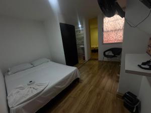 a bedroom with a white bed and a wooden floor at Hotel sahara in Medellín